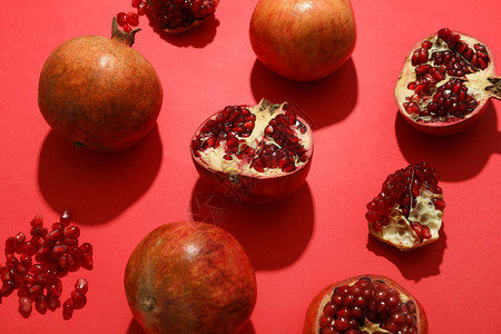 平躺在红色背景上的石榴多汁的水果图片