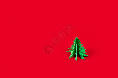 冬季节日快乐的节日贺卡用折纸制成的绿色枞树在假日红色背景下的镜头贺卡图片