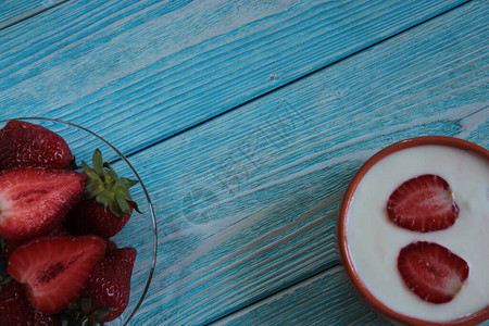 蓝色木桌上的草莓和奶油图片