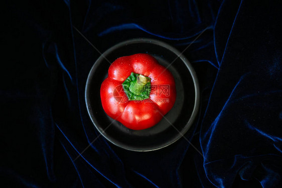 深蓝色背景上黑色盘子上的圆形红色pereklezhatsya它有一条绿色的小奶尾巴顶视图片