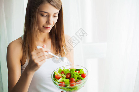 饮食年轻女人吃沙拉拿着混合沙拉图片