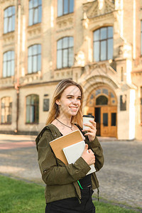 有吸引力的微笑白种人年轻女学生拿着学生书拿走大学前的咖啡大学生在校园附近享受阳光和咖图片