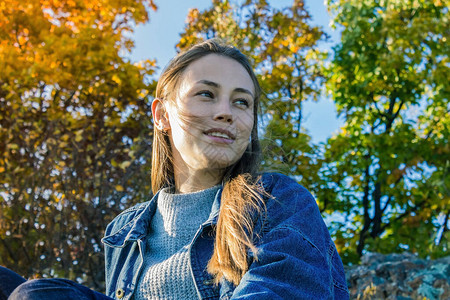 秋天的森林公园黄色和绿色的树叶牛仔夹克的年轻现代女孩休闲风背景图片