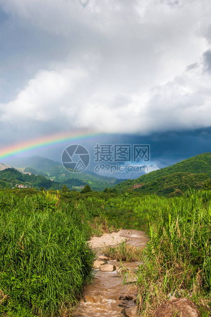 热带山谷上多彩的虹在雨中风景优美的图片