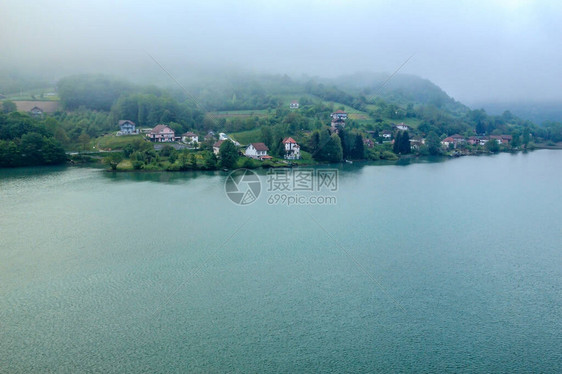 在寒冷的夏日早晨雾在山上向湖面蔓延图片
