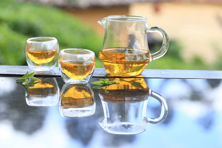茶  山透明的锯齿和玻璃杯中的热清茶在自然中反射泰国湄宏背景