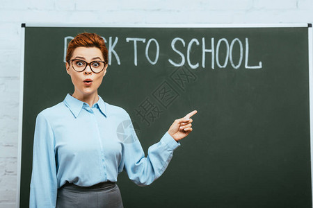 老师在黑板附近用手指着有返校登记表的教图片
