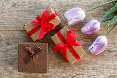 装有红丝带的礼品盒和木板上漂亮的利拉克郁金香顶级视图节假日赠图片