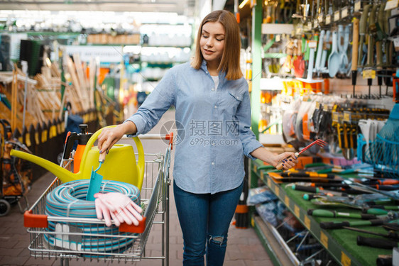 女顾客在货架上挑选园艺工具图片