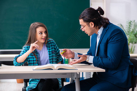 年轻英俊的教师和教室中的女学图片