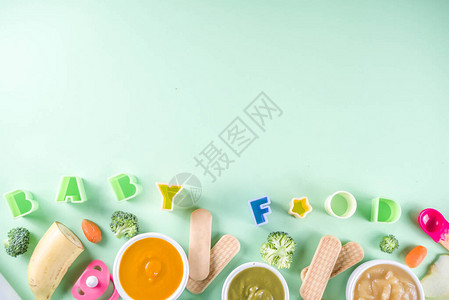 婴幼儿食品有蔬菜水果泥绿色橙色黄色的碗西兰花胡萝卜香蕉苹果用品和玩具绿色背景平躺顶图片