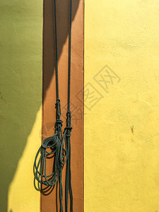 绿色绳索挂在黄色上有棕色水泥墙背景图片