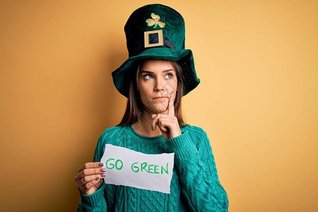 戴着绿色帽子庆祝圣帕特里克节的年轻美女拿着信息严肃的脸思考问题图片