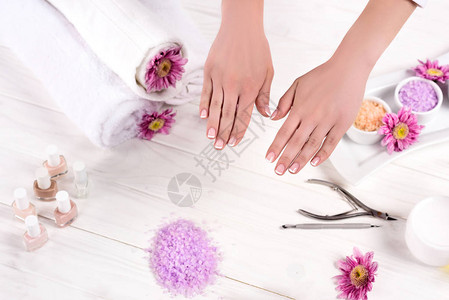 用毛巾鲜花指甲油丰富多彩的海盐奶油容器和美容院修指甲工具在餐桌上部图片