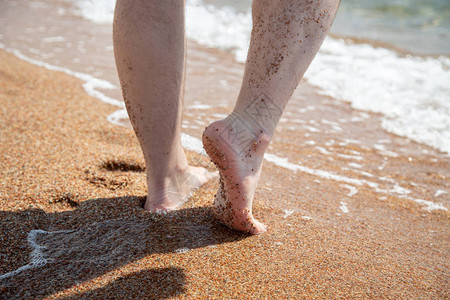 走 脚赤脚在海滩上的特写走在水边的沙滩上假期和旅行的概念男人的脚