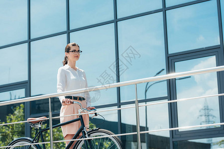 身戴眼镜的漂亮女商人站在建筑附近图片