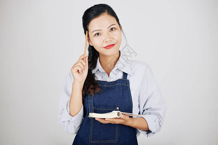 漂亮的女服务员用铅笔刮额头在教科书中图片