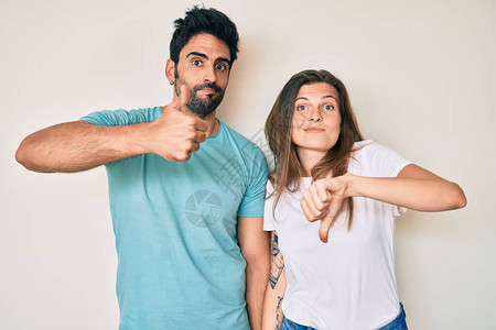 美丽的年轻夫妇的男朋友和女朋友一起做拇指上下分歧和同意的表达图片