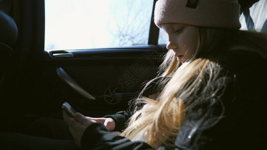 长着金发的小女孩坐在行驶的汽车后座上图片