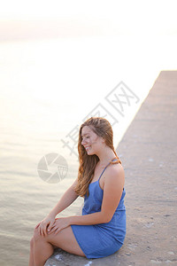 坐在码头上并穿着蓝色防晒服的年轻女子图片