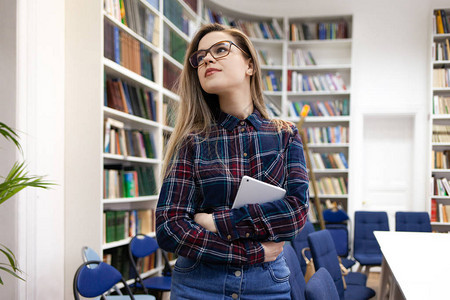 美丽的年轻女学生站在大学图书馆的书房里图片