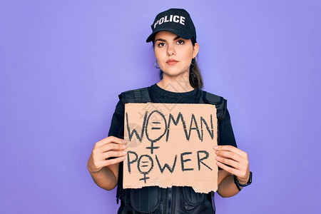 身穿防弹背心制服的警察妇女拿着女权力抗议纸板图片