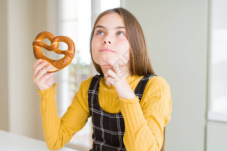 美丽的年轻女孩子吃德国小吃点心咸脆饼严肃的面对现实思考问题图片