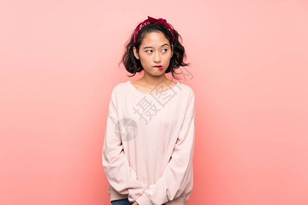 亚裔年轻女在孤立的粉红背景与混乱图片