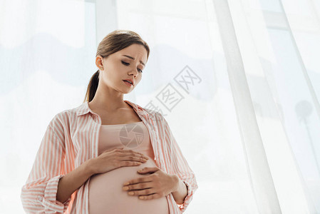 低角度观察怀孕妇触摸腹部和图片