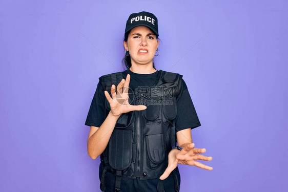 穿着紫色背景的安全防弹背心制服的年轻女警厌恶表情图片