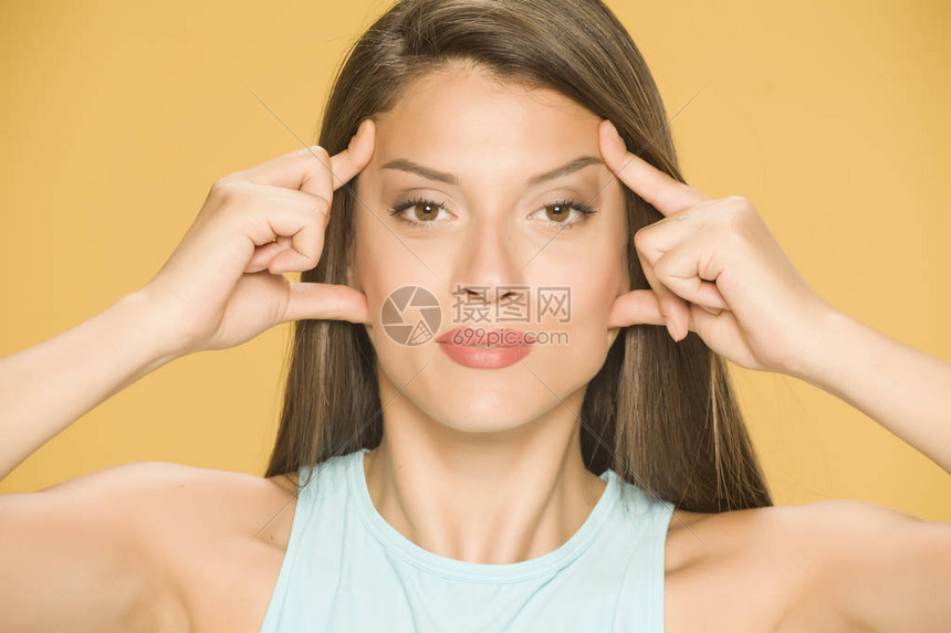 一位年轻女子用黄色背景的双手紧图片