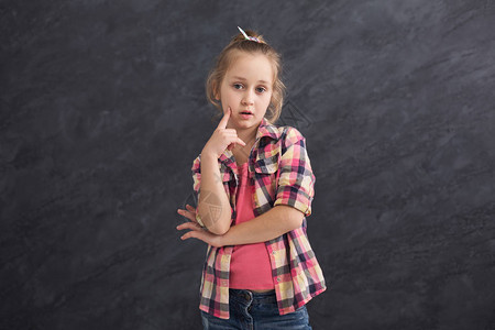站在灰色背景和思想上思考的有想象力的小女孩图片
