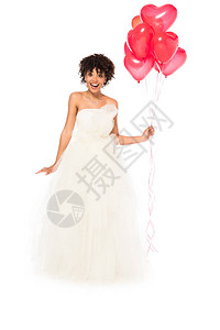 身着白色孤立的结婚礼服站着拿心形气球图片