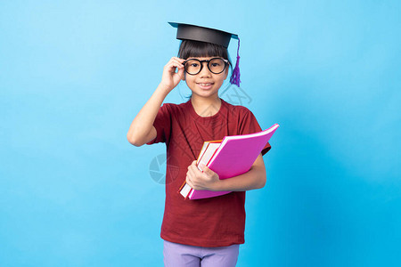 年轻女学生触摸眼镜和照相机戴学位帽和持有书籍图片
