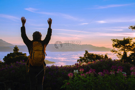 有背包的年轻女旅游者站着观赏大自然美丽的风景和雾在山顶图片