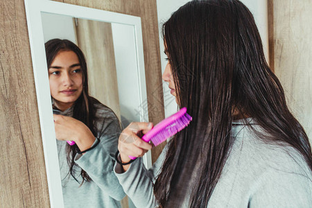 一个女孩在镜子前用梳子理头发的无重点反图片