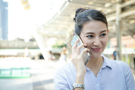 一个美丽的西方女人用她的智能手机在户外交谈她开心地笑着技术图片