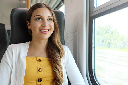坐在火车上看着窗外的年轻女旅图片