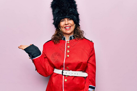 中年美丽的威尔士守卫妇女穿着粉红色背景的传统制服图片