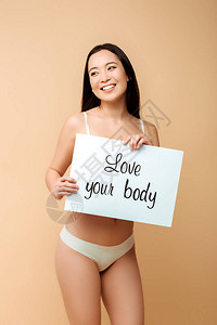 喜悦的亚裔女孩拿着标语牌爱着你的身体在蜜蜂背景图片