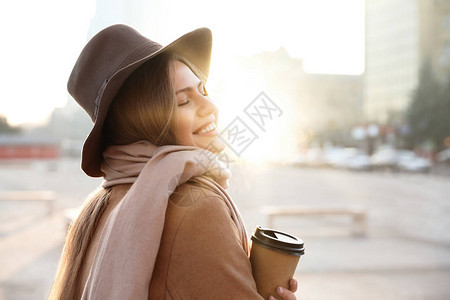 早上在城市街道上喝杯咖啡的年轻女子图片