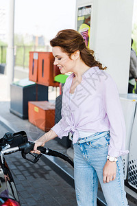 在加油站用汽油给汽车加油时拿着燃油图片