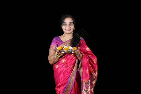 一位中年印度妇女带着pujathali等待传统上在黑色工作室背图片