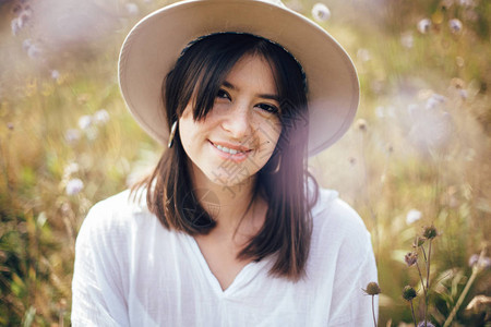 快乐的时髦女孩戴着帽子在野花草地上放松图片