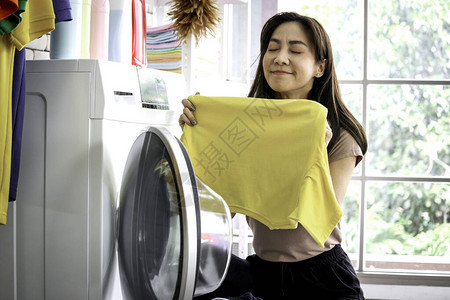 笑得开心的亚洲美女在洗衣房用洗衣机洗衣服图片
