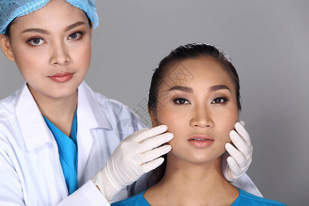 亚洲医生护士在整形手术前检查脸颊骨结构并向患者注射美容化学注射器图片