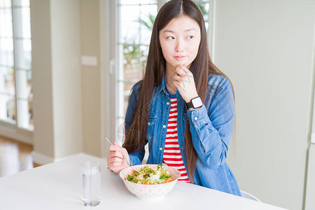 美丽的亚洲女人吃健康的意大利面沙拉严肃地面对着思考问题图片