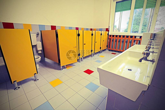 一间没有孩子的幼儿园浴室上的洗浴盆和黄色门图片