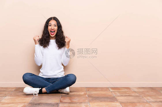 坐在地板上庆祝胜利获胜的年轻女士图片
