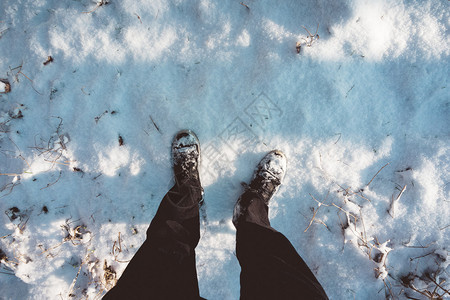 以第一人称视角俯视一个人站在新白的冬雪中的腿和鞋子图片